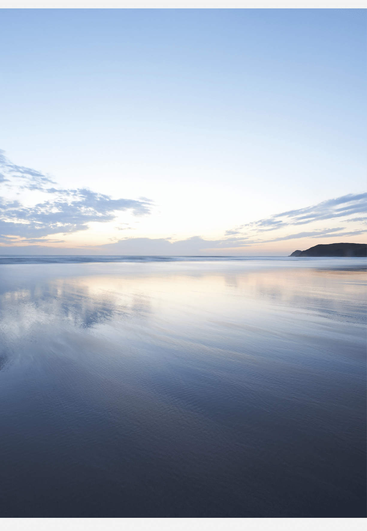 View out to a beautiful seascape reflected in the shallow waters at dusk 