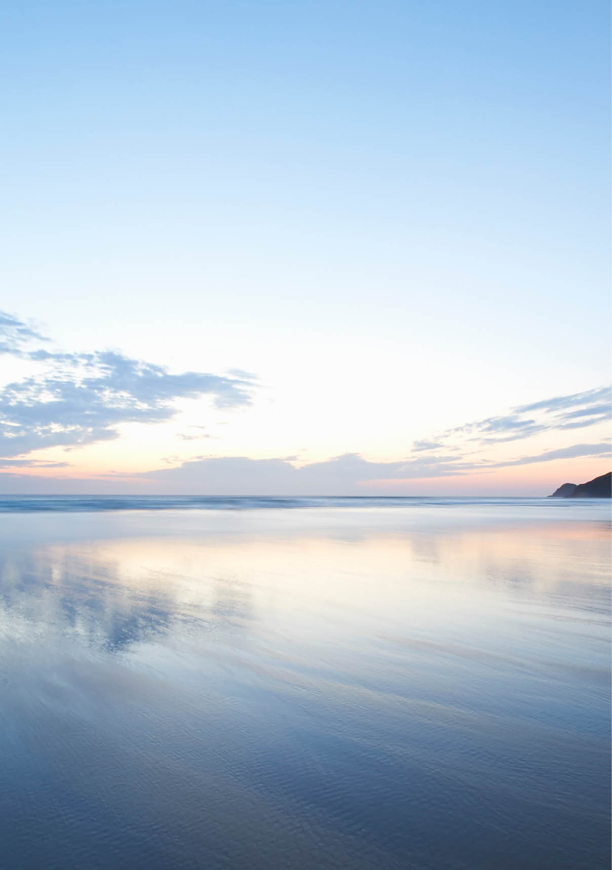 View out to a beautiful seascape reflected in the shallow waters at dusk 